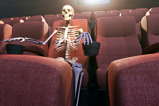 skeleton-in-an-empty-movie-theatre-representing-bored-to-death-and-picture-id1220758446