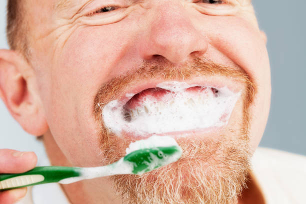 mature-bearded-man-smiles-toothpaste-foaming-as-he-brushes-teeth-picture-id687415004
